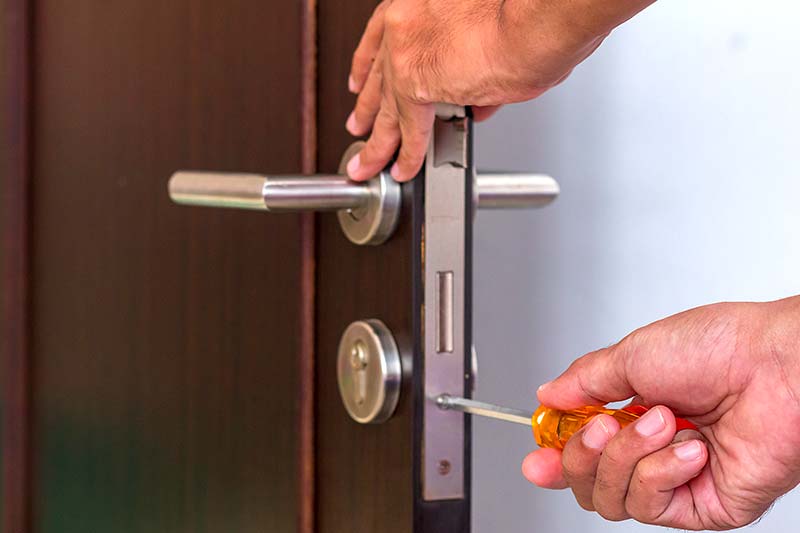 Profissional instalando fechadura residencial em porta de madeira